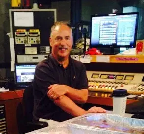 Allan Camp in a radio studio, seated at the on-air console